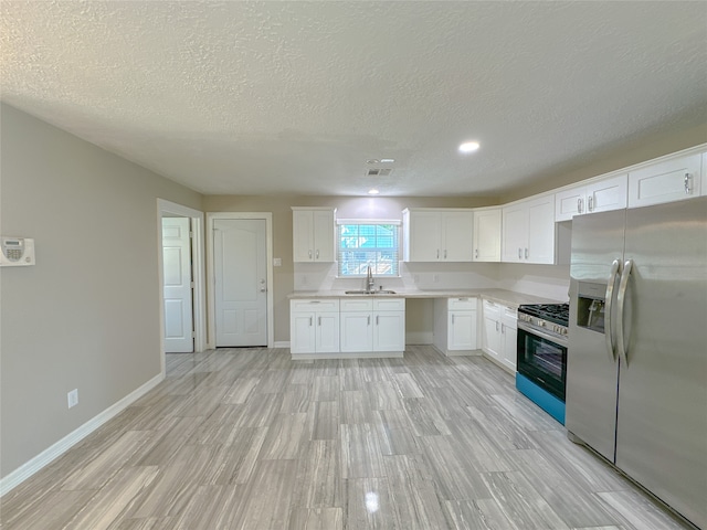 kitchen featuring white cabinets, a textured ceiling, appliances with stainless steel finishes, and light hardwood / wood-style floors