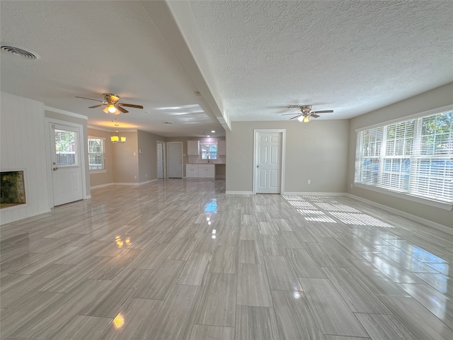 unfurnished living room with ceiling fan, a textured ceiling, light wood-type flooring, and beam ceiling