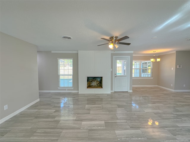 unfurnished living room featuring ceiling fan with notable chandelier and a textured ceiling