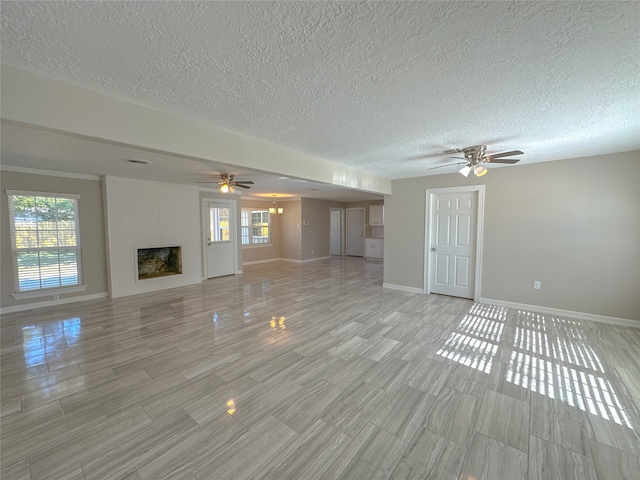 unfurnished living room with ceiling fan, light wood-type flooring, a wealth of natural light, and a textured ceiling