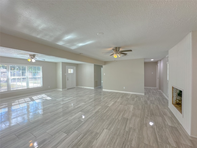 unfurnished living room featuring ceiling fan, light hardwood / wood-style flooring, and a textured ceiling