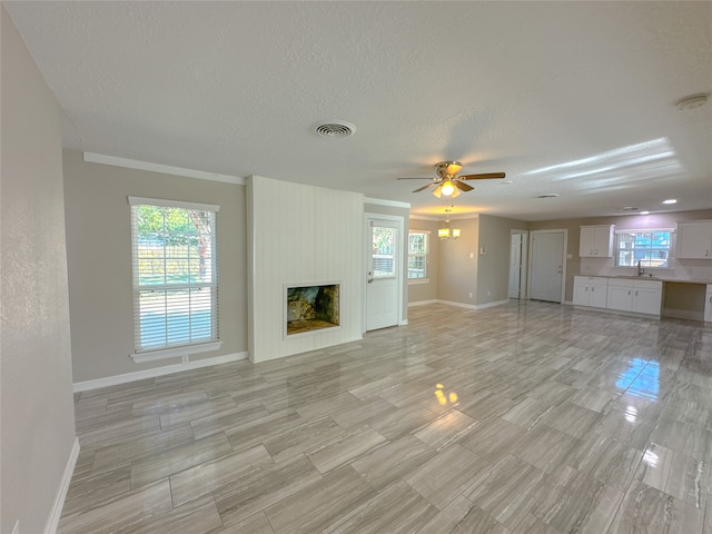 unfurnished living room featuring a fireplace, ceiling fan, and a textured ceiling