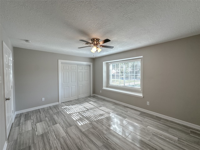 unfurnished bedroom with light wood-type flooring, ceiling fan, a closet, and a textured ceiling