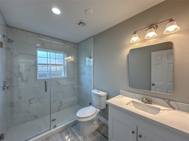 bathroom featuring vanity, a textured ceiling, toilet, and an enclosed shower