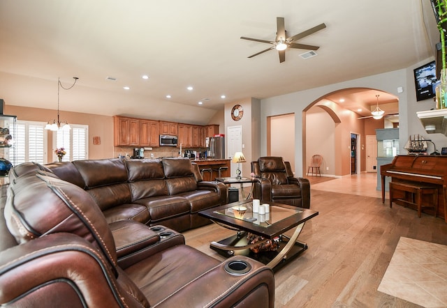 living room featuring ceiling fan with notable chandelier and light wood-type flooring