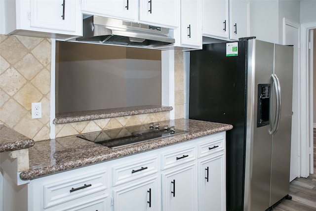 kitchen featuring stainless steel fridge, tasteful backsplash, white cabinetry, black stovetop, and hardwood / wood-style floors