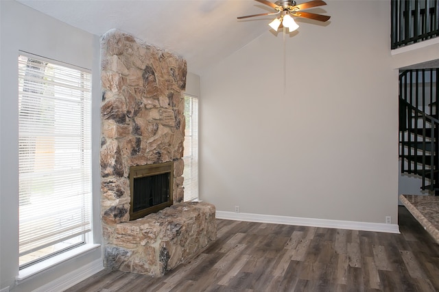 living room featuring vaulted ceiling, a fireplace, dark hardwood / wood-style flooring, and a wealth of natural light