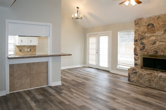 unfurnished living room featuring ceiling fan with notable chandelier, a fireplace, dark hardwood / wood-style flooring, and high vaulted ceiling