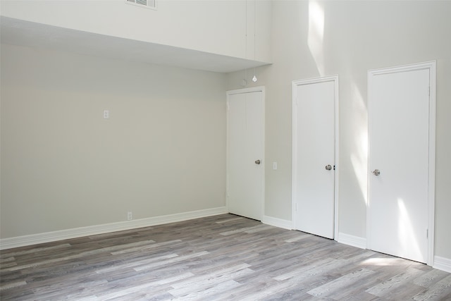 unfurnished bedroom with a towering ceiling and light hardwood / wood-style flooring