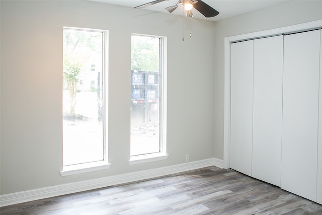 unfurnished bedroom featuring light wood-type flooring, ceiling fan, and a closet