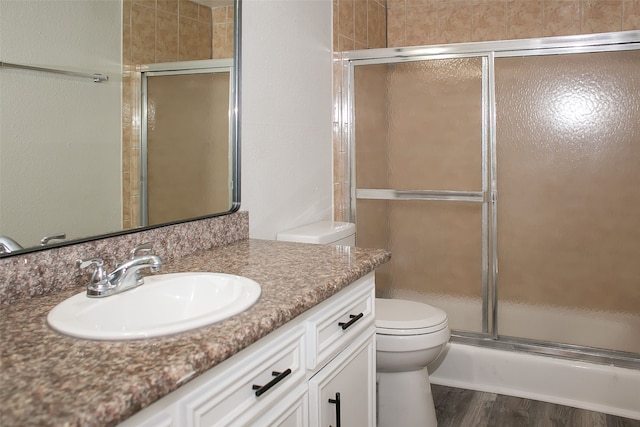 bathroom featuring wood-type flooring, a shower with door, vanity, and toilet