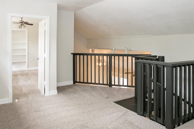 hallway featuring vaulted ceiling, carpet flooring, and a textured ceiling