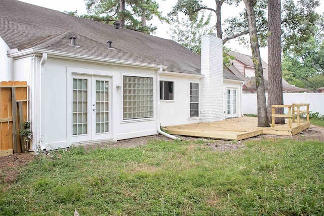 back of house featuring a wooden deck, french doors, and a lawn