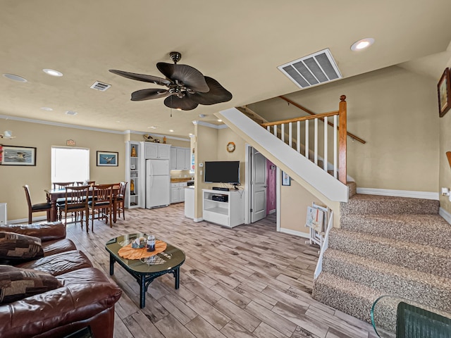 living area featuring stairs, visible vents, baseboards, and a ceiling fan