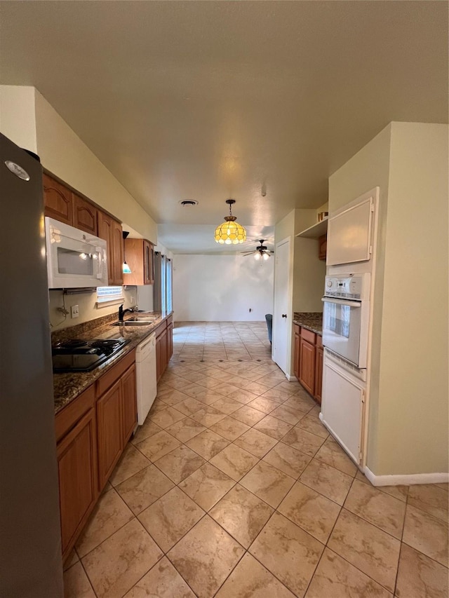 kitchen featuring ceiling fan, dark stone countertops, white appliances, and sink