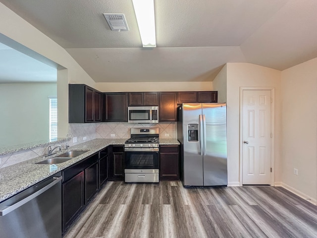 kitchen with hardwood / wood-style flooring, appliances with stainless steel finishes, sink, and vaulted ceiling