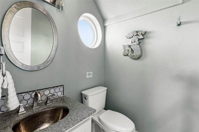 bathroom with vanity, toilet, and lofted ceiling