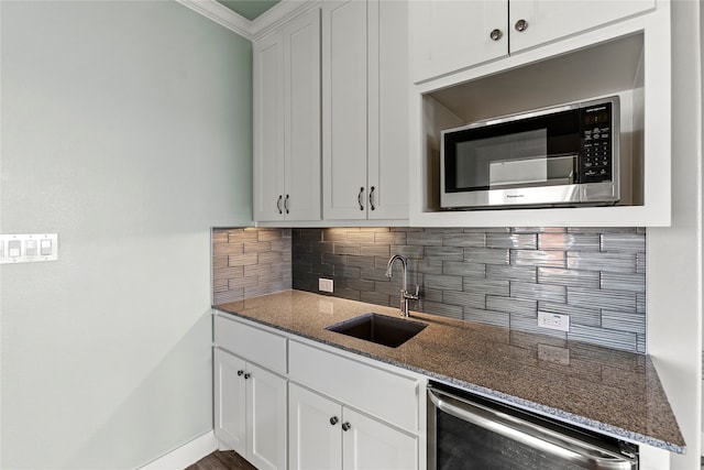 kitchen with stainless steel microwave, sink, dark stone counters, and white cabinets