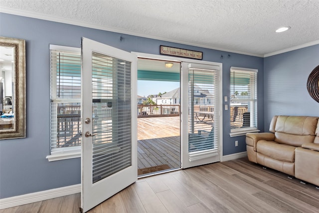 entryway featuring french doors, a textured ceiling, ornamental molding, and light wood-type flooring