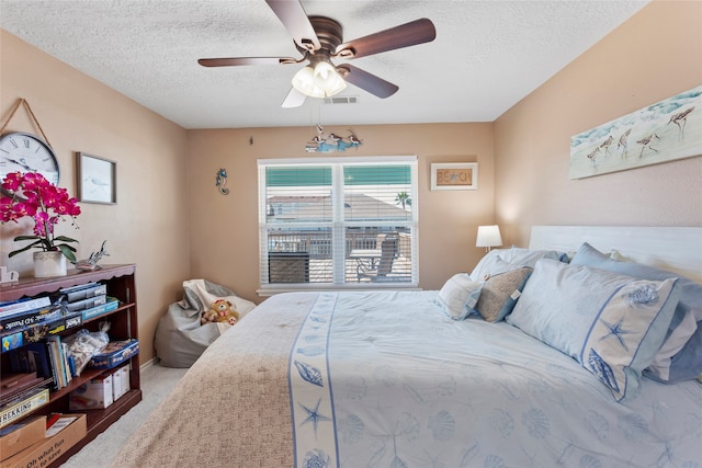 bedroom with ceiling fan, a textured ceiling, and carpet floors