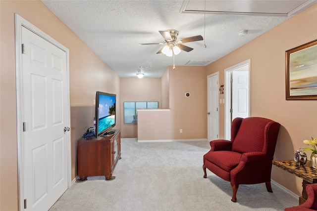 sitting room with ceiling fan, a textured ceiling, and light colored carpet