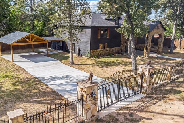 24578 Derry St, Hempstead, TX 77445 - view of front of house featuring a fenced front yard, a carport, roof with shingles, a gate, and stone siding