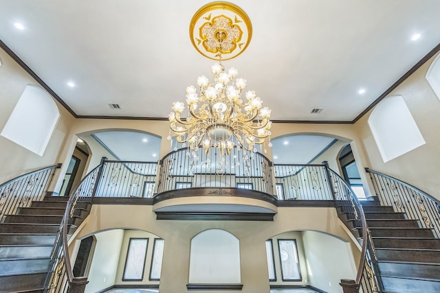 staircase with crown molding, a high ceiling, and a chandelier