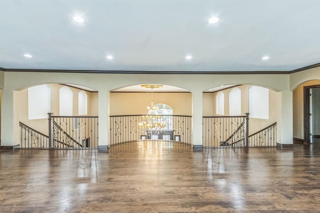 empty room with crown molding, a chandelier, and dark hardwood / wood-style floors