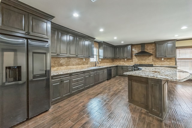 kitchen featuring stainless steel built in refrigerator, wall chimney exhaust hood, dark hardwood / wood-style floors, and a wealth of natural light