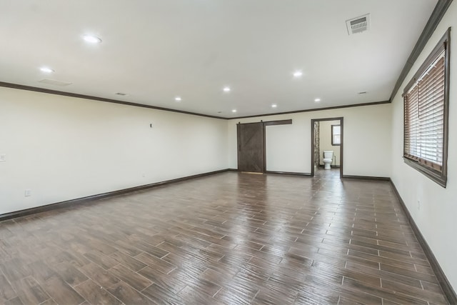 spare room with a barn door, dark hardwood / wood-style floors, and ornamental molding