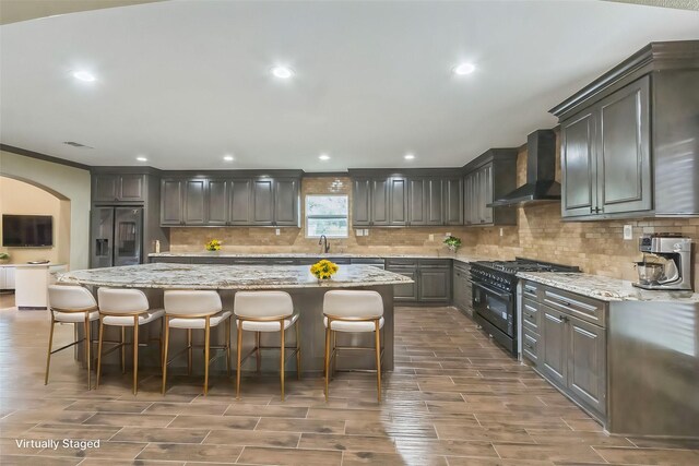 24578 Derry St, Hempstead, TX 77445 - kitchen with wall chimney exhaust hood, high end black range oven, stainless steel fridge, wood tiled floors, and recessed lighting