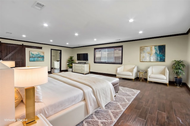 bedroom with a barn door, crown molding, and hardwood / wood-style floors