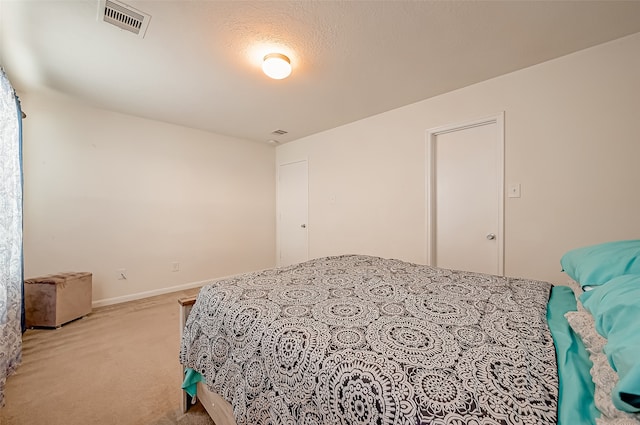 bedroom with a textured ceiling and light colored carpet