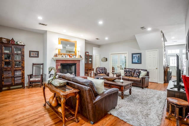 living room with light hardwood / wood-style flooring, a wealth of natural light, and a brick fireplace