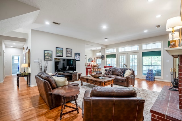 living room with a fireplace, french doors, and light hardwood / wood-style flooring