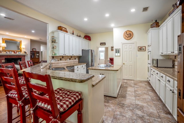 kitchen featuring a center island, sink, appliances with stainless steel finishes, a kitchen bar, and kitchen peninsula