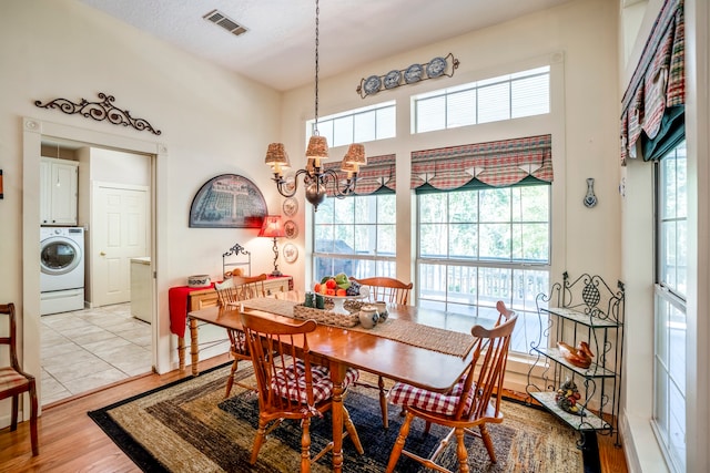 dining area with washer / clothes dryer, plenty of natural light, a notable chandelier, and light wood-type flooring