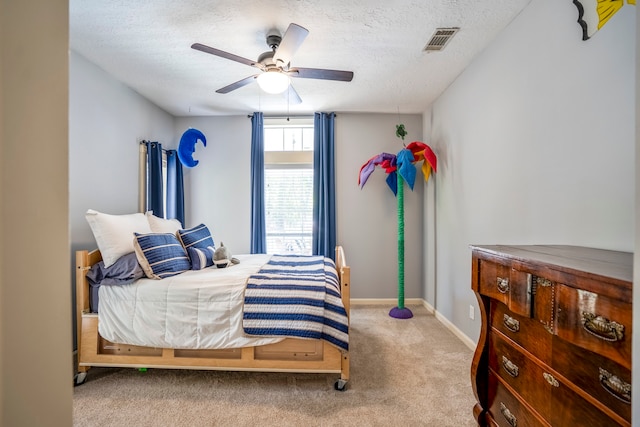 carpeted bedroom featuring ceiling fan and a textured ceiling