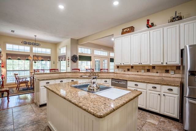 kitchen with kitchen peninsula, appliances with stainless steel finishes, pendant lighting, a center island, and white cabinetry