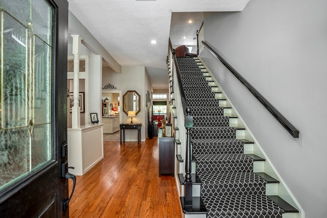 stairway with wood-type flooring and a textured ceiling