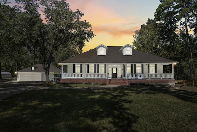 view of front of home with covered porch, a yard, a garage, and an outdoor structure