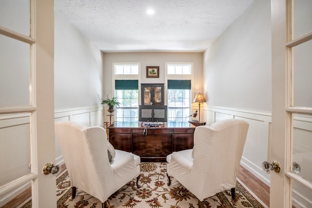 sitting room featuring french doors, light hardwood / wood-style floors, and a textured ceiling