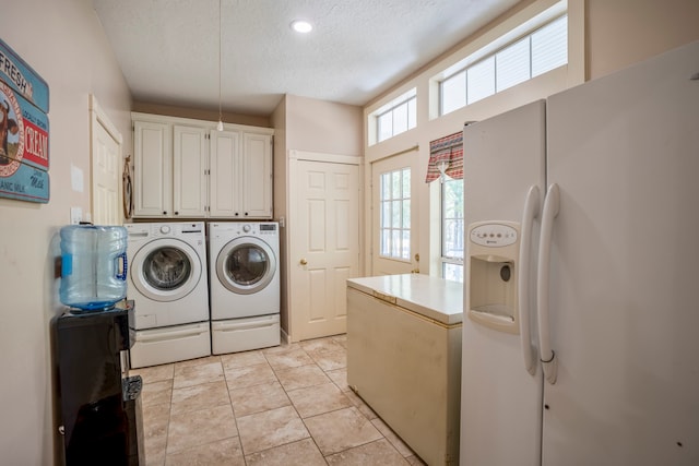 laundry area featuring separate washer and dryer, light tile patterned flooring, cabinets, and a textured ceiling