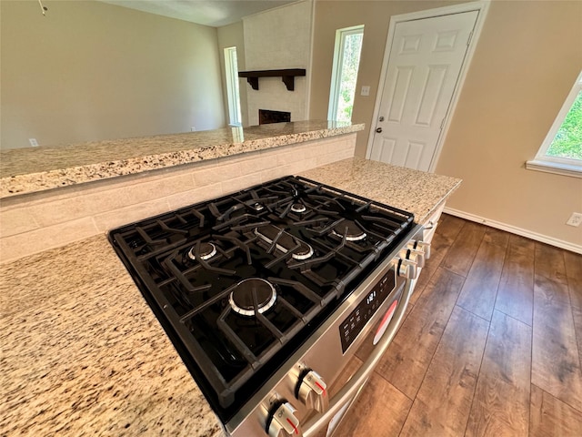 kitchen with light stone countertops, dark hardwood / wood-style floors, and stainless steel range with gas stovetop