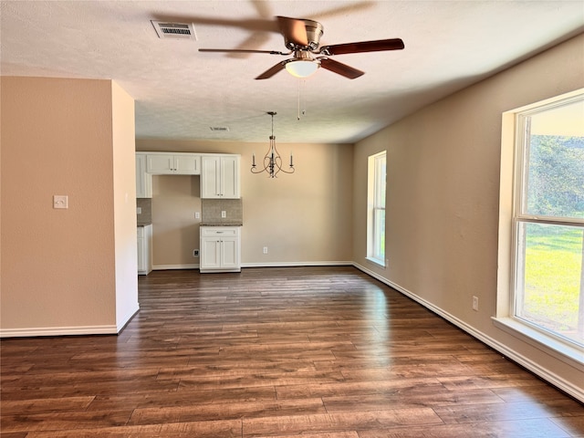 empty room with ceiling fan with notable chandelier, a textured ceiling, and dark hardwood / wood-style flooring