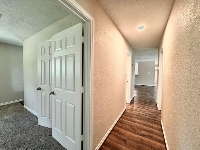 hallway with a textured ceiling and dark wood-type flooring