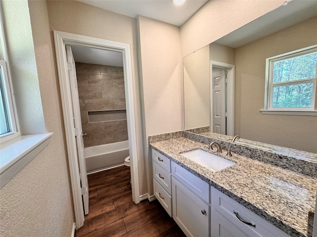 full bathroom with toilet, vanity, tiled shower / bath combo, and hardwood / wood-style flooring