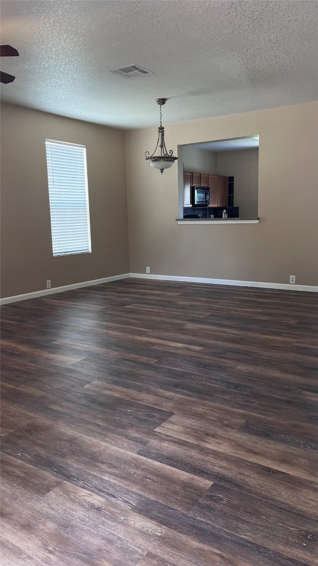 empty room featuring ceiling fan, dark hardwood / wood-style floors, and a textured ceiling