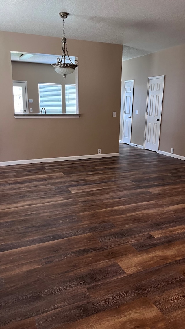 empty room with a textured ceiling and dark hardwood / wood-style floors