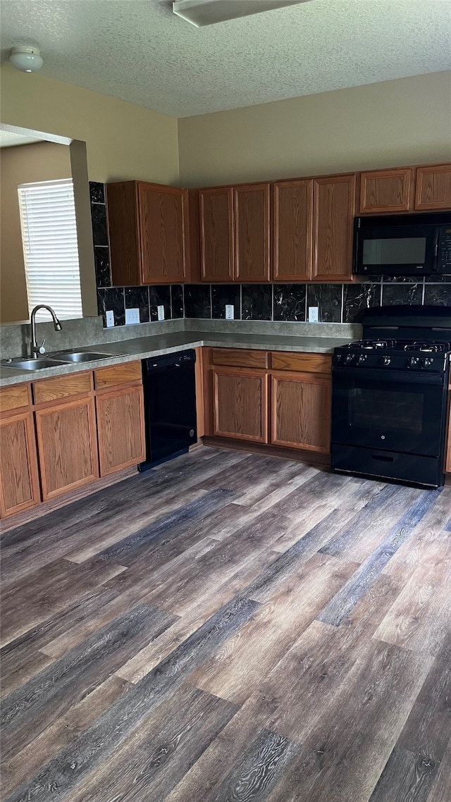 kitchen with black appliances, backsplash, sink, dark hardwood / wood-style flooring, and a textured ceiling